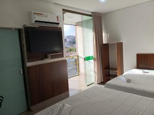 a room with a bed and a tv and a bed sidx sidx sidx at Hotel Esmeralda Verde in Teófilo Otoni