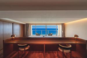 a room with a desk with a view of the ocean at RAV RESORT Okinawa in Yomitan