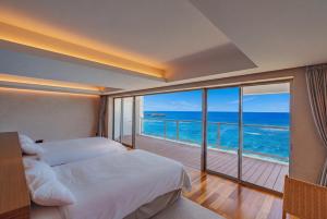 a bedroom with a bed and a balcony with the ocean at RAV RESORT Okinawa in Yomitan +38 photos