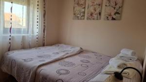 a small bedroom with a bed with a white blanket at Apartman Lavanda in Temerin