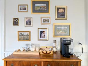 a coffee maker on top of a wooden table with pictures on the wall at Red Roof Guesthouse in Cobourg +6 photos