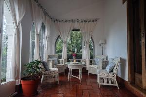 a room with chairs and a table and windows at Posada los Cedros in La Cumbre
