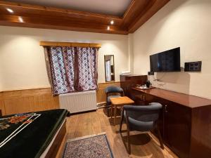 a room with a bed and a desk and a television at The Juniper Ladakh Guest House in Kargil