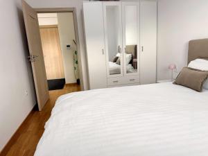 a bedroom with a large white bed and a mirror at Maison Budva in Bečići