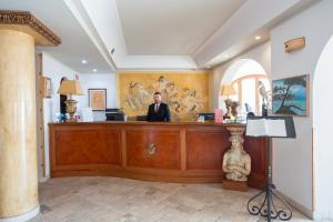 a man in a suit sitting at a reception desk at Hotel Tritone Lipari in Lipari +114 photos