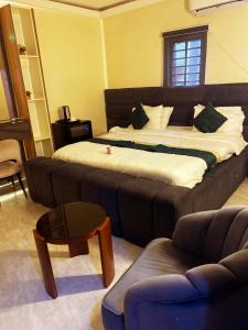 a bedroom with a large bed with a couch and a table at NH Norvits Hotel in Agbor