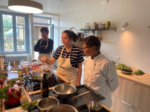 three people standing in a kitchen preparing food at Cense des Possibles, Forêt et Prairie in Darcey