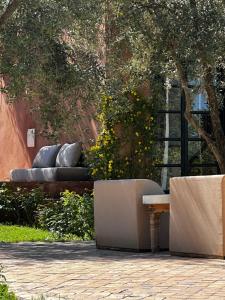 two benches with pillows sitting under a tree at Villa Quince in Ouirgane