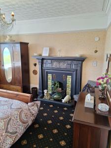 a living room with a fireplace and a bed and a table at Moon River in Goodwick