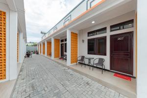 a row of buildings with tables and chairs on a sidewalk at RedDoorz Plus at Orange Diponogoro Palangkaraya in Palangkaraya