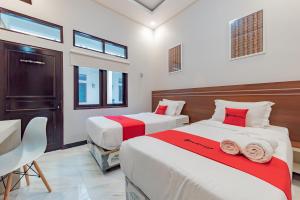 a bedroom with two beds and a table and chairs at RedDoorz Plus at Orange Diponogoro Palangkaraya in Palangkaraya +15 photos