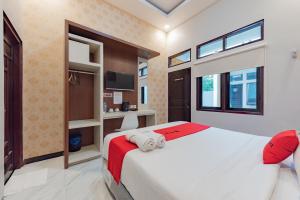 a bedroom with a large white bed and windows at RedDoorz Plus at Orange Diponogoro Palangkaraya in Palangkaraya