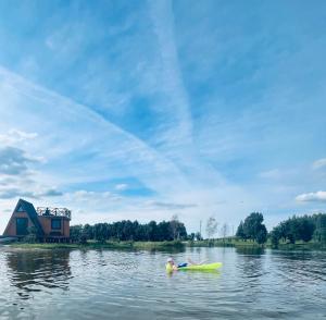 a man laying on a kayak in the water at Liepų namelis - Linden Shore in Miroslavas
