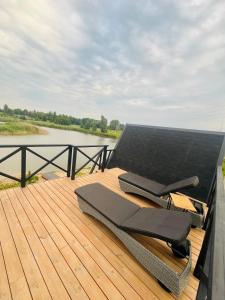 a bench on a deck next to a body of water at Liepų namelis - Linden Shore in Miroslavas