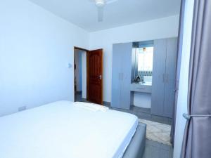 a white bedroom with a bed and a kitchen at Kenya coast stays in Nyali