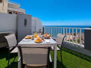 a table with food on a balcony with the ocean at Incredible Sunsets in Puerto Rico de Gran Canaria