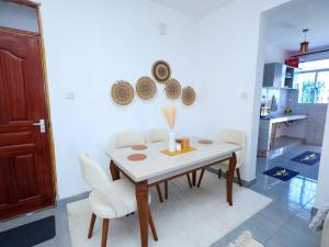 a dining room with a white table and white chairs at Kenya coast stays in Nyali