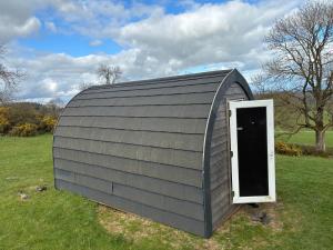 a small shed with a door in a field at Hillside Pod in Oswestry
