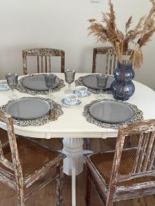 a white table with plates and a vase on it at Charzykówka Domek na Kaszubach in Charzykowy