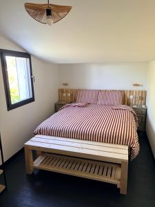 a bedroom with a bed with a bench in it at L Amy-Côtier in Saint-Pierre-dʼOléron