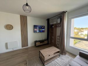 a living room with a couch and a table and a window at Studio côté soleil in Saint-Jean-de-Monts