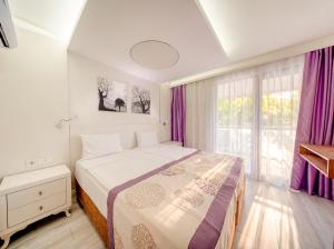 ein Schlafzimmer mit einem großen Bett und lila Vorhängen in der Unterkunft Tropic Beach Resort Hotel in Side