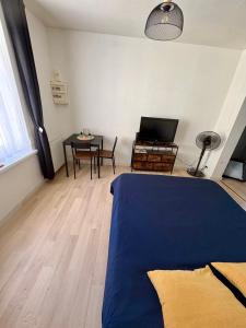 a room with a bed and a table and a television at Pause Confort Studio idéal centre ville in Gravelines