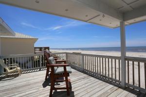 a rocking chair on a deck with a view of the beach at Buckleys Beach House by Pristine Property Vacation Rentals in Indian Pass