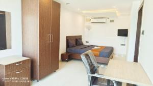a bedroom with a bed and a desk and a cabinet at Apex Inn Gulf View in Bangalore
