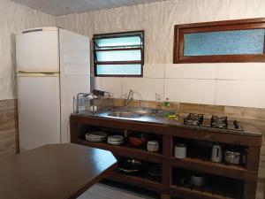 a kitchen with a sink and a refrigerator at Apartamentos do Centrinho do Rosa in Imbituba