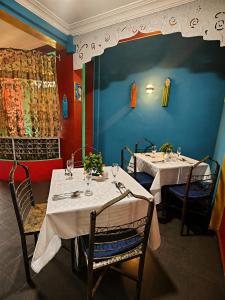 two tables in a restaurant with white table cloths on them at Hôtel la medina in Antananarivo