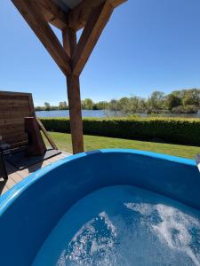 a blue hot tub on a patio with a view of the water at Lake View Retreats in Rickmansworth