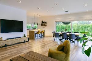 a dining room and living room with a large screen tv at Villa Tomaté in Velika Buna