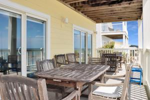 a wooden table and chairs on a patio with the ocean at Villa del Sol by Pristine Property Vacation Rentals in Cape San Blas