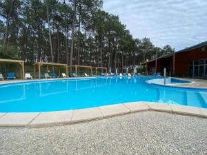 a large blue swimming pool with chairs and trees at Chalet à l'océan in Bias