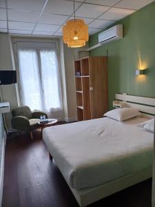 a bedroom with a large bed and a chair at Hotel Le Colibri in Aix-les-Bains