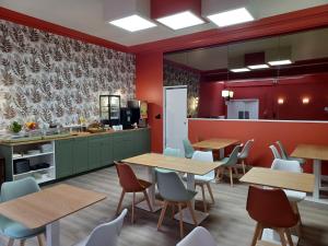 a restaurant with tables and chairs and a kitchen at Hotel Le Colibri in Aix-les-Bains