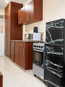 a kitchen with wooden cabinets and a black oven at Kin Bnb in Ruaka