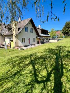 a house with a shadow of a tree on a lawn at Zeit/-Los in Irdning
