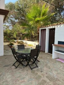 a glass table and chairs on a patio at Casa Las Adelfas in Isla Cristina
