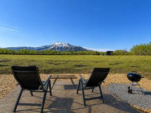 two chairs and a table with a mountain in the background at XYZ Niseko in Niseko