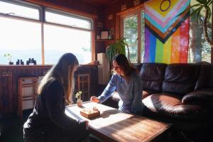 two women playing a board game on a coffee table at Loch Ness Lochside Hostel - Over 16s Only in Invermoriston
