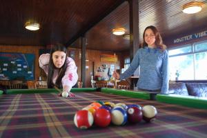 two girls playing snooker at a pool table at Loch Ness Lochside Hostel - Over 16s Only in Invermoriston