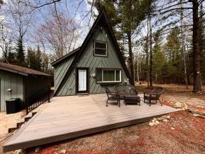 a home with a deck with chairs and a house at Emerald Escape in Grayling