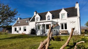 a white house with a black roof at Donmar Cottage in Skeabost