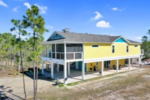 a yellow house with a blue roof at Dolphin Daze by Pristine Properties Vacation Rentals in Saint Joe Beach