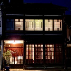 a building with windows and a gate at night at 金沢町家ゲストハウスかるた in Kanazawa