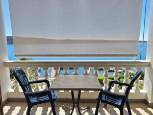a table and two chairs on a balcony with a window at Apartments and Rooms Vinko in Barbat na Rabu