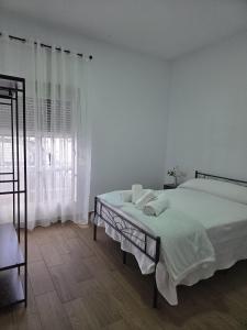 a white bedroom with a bed and a window at El Zamora in Sanlúcar de Barrameda