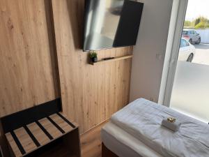a small bedroom with a bed and a flat screen tv at AS-Hotel NOM in Northeim